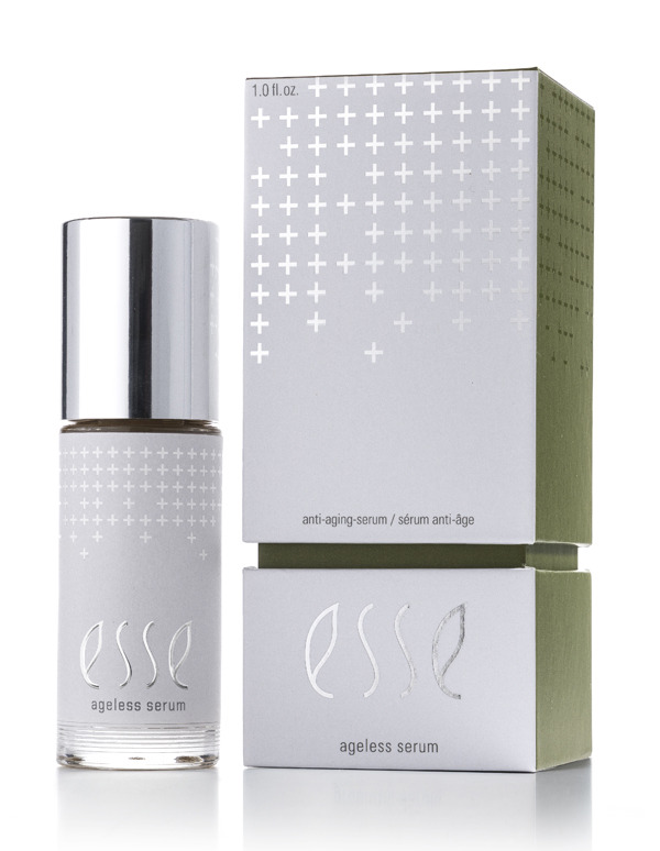 A bottle of Esse Ageless Serum with a silver cap stands beside its matching box, which has a minimalist design with silver text and cross patterns on a pale green and white background.